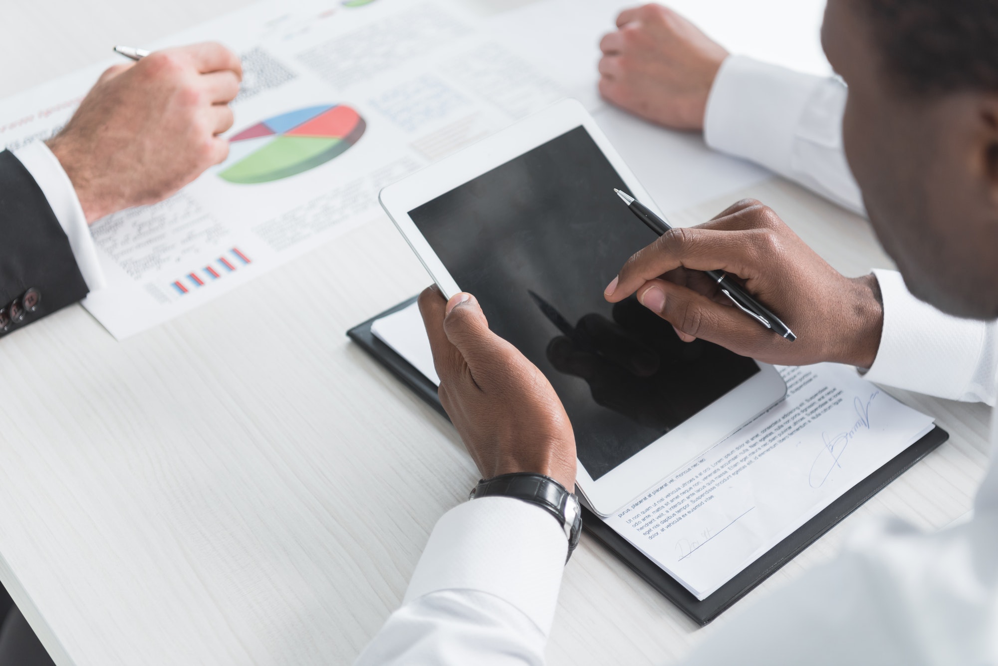 cropped-shot-of-african-american-businessman-using-tablet-during-business-meeting-with-colleagues.jpg